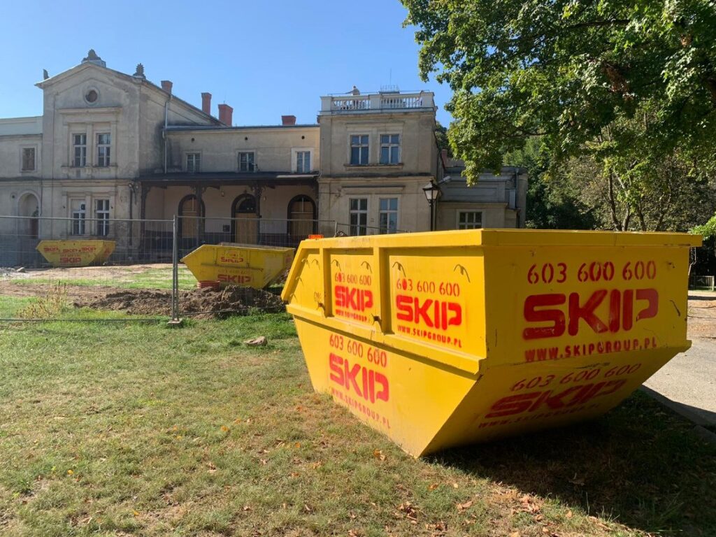żółty kontener SKIP na trawniku przed pałacem